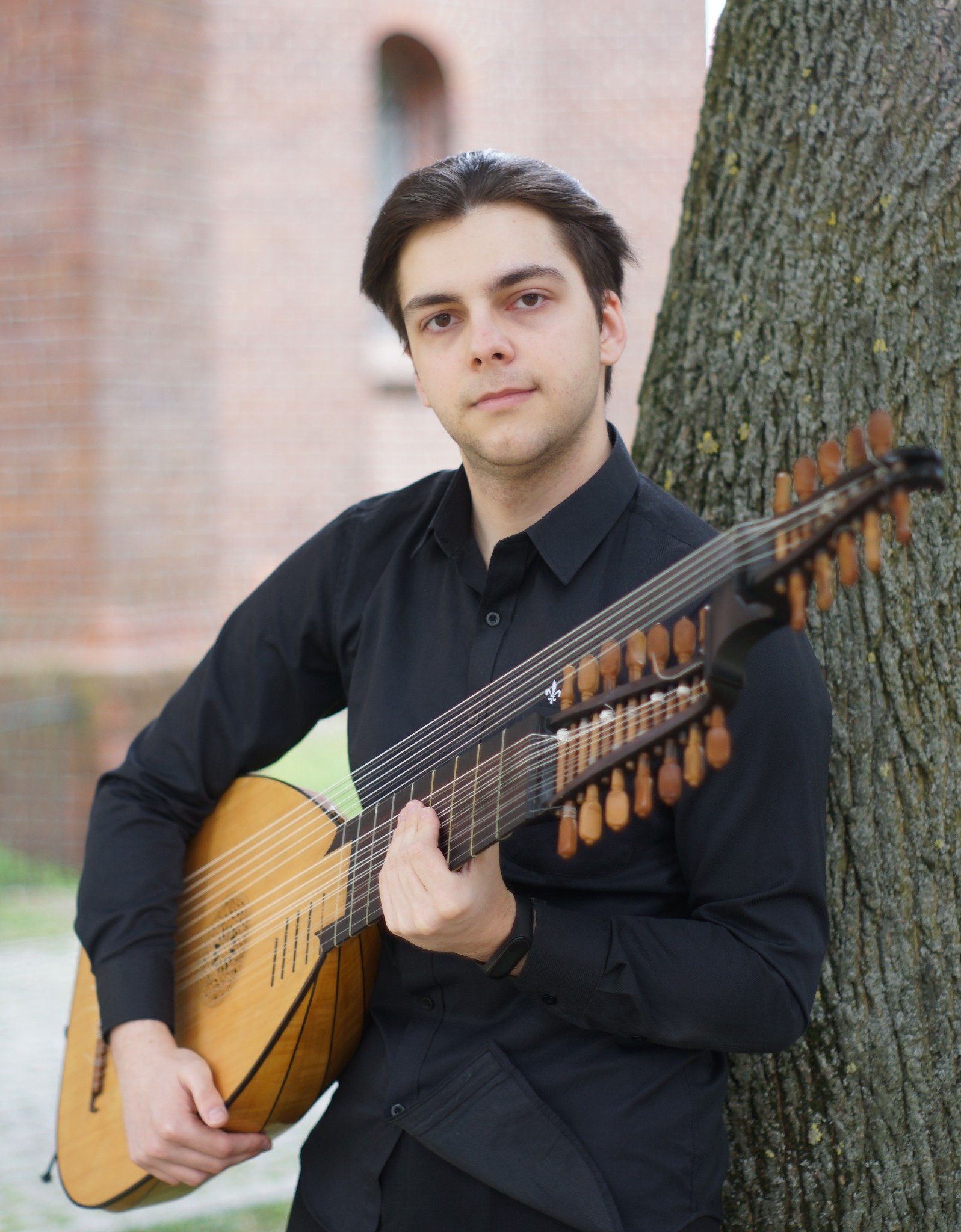 Stefan Jasiniefta holding a baroque lute beside a tree